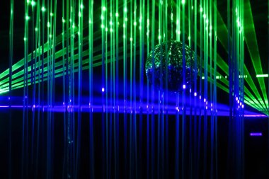 Siyah arka planda yeşil ve mavi lazer ışınları. Lazer ışın akışını gösterir