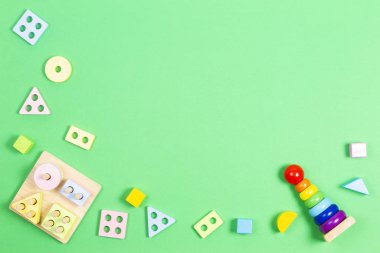Early childhood development puzzle baby toys. Wooden pastel color geometry educational toy for children and colorful geometric stacking blocks tower toy on light green background.