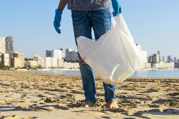 Clean beach from plastic. Volunteer picking up plastic bottle trash from the beach and putting into plastic bag for recycle — Stok fotoğraf