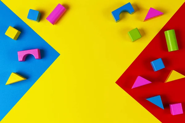 Wooden colorful blocks on geometric yellow blue red background. Top view — Stock Photo, Image