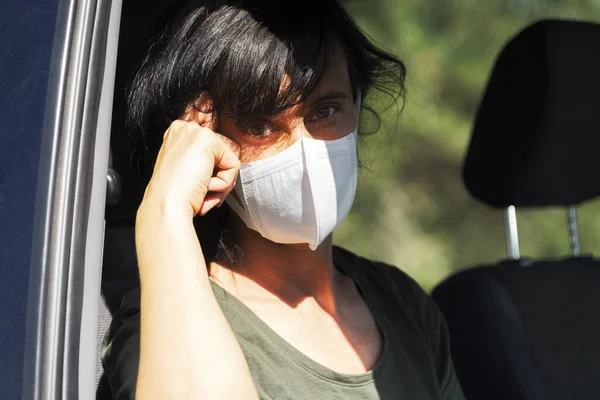Nebezpečí koronového viru. Žena s ženskou ochrannou obličejovou maskou sedí v autě — Stock fotografie