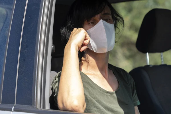 Danger of corona virus. Woman with women protective face mask sitting in the car