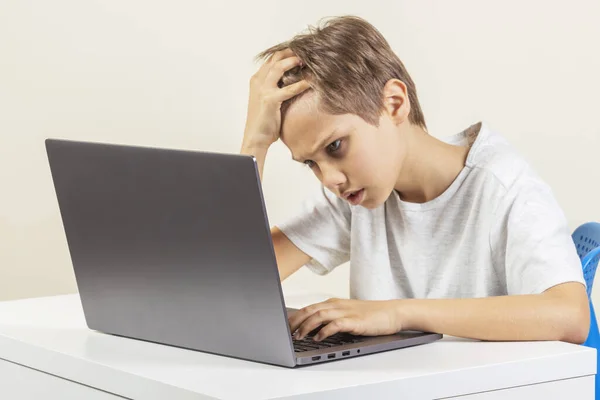 Cansado menino decepcionado com computador portátil sentado à mesa — Fotografia de Stock