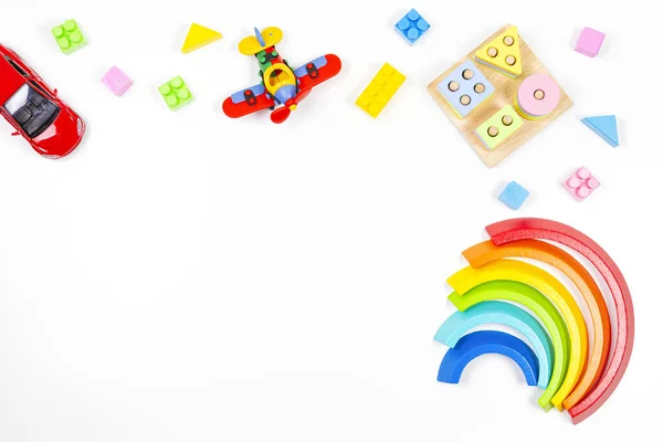 幼儿玩具背景。木制教育几何积木玩具、彩虹、飞机、汽车和白色背景的彩色积木 — 图库照片