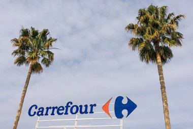 Finestrat, İspanya - 5 Mart 2020: Carrefour süpermarketinde mavi gökyüzü ve palmiye arkaplanlı Carrefour logosu