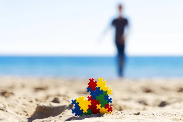 Autism awareness day concept. Colorful puzzle autism awareness heart on beach sand and silhouette of autistic kid boy — 스톡 사진