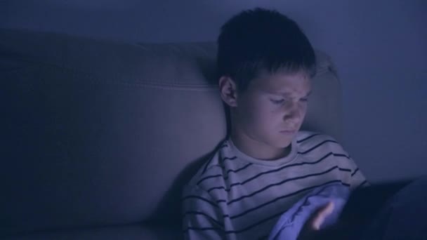 Adolescente niño usando tableta PC en casa por la noche. Niño jugando juegos de ordenador, ver vídeo, navegar en la red — Vídeo de stock