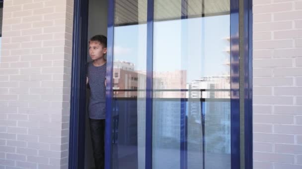 El adolescente abre la puerta de cristal, mira a su alrededor, cierra la puerta y regresa a casa triste y decepcionado porque no puede salir. Cuarentena en casa — Vídeos de Stock