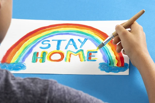 Pintura infantil durante la cuarentena en casa. Arco iris con palabras Quédate en casa. Campaña de medios sociales para la prevención del coronavirus — Foto de Stock