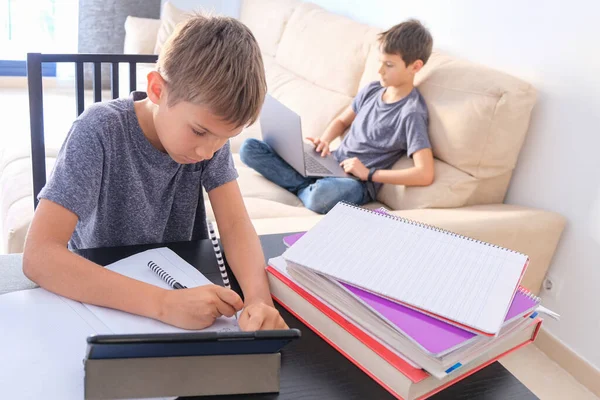 Tecnología, educación, aprendizaje en línea, aprendizaje a distancia en el hogar. Boy empezar a hacer los deberes de matemáticas con los libros y otro chico usando el ordenador portátil para la lección en línea en casa — Foto de Stock