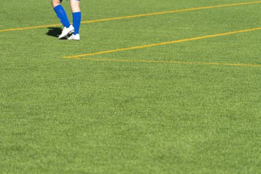 Genç futbolcu ayakları boş yeşil çimen futbol sahasında