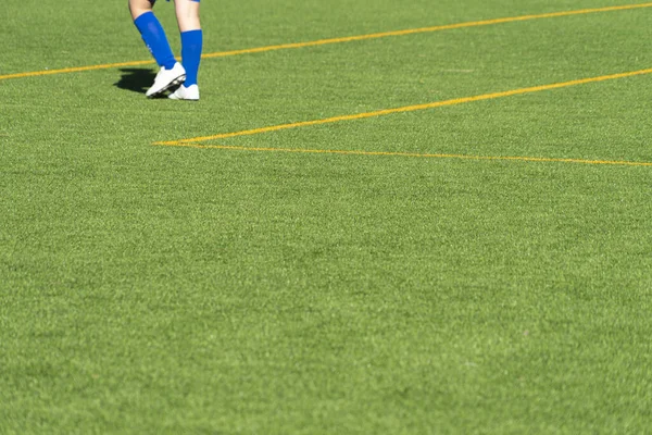 Młodzież piłkarz nogi na pustej zielonej trawy piłki nożnej boisko do ćwiczeń — Zdjęcie stockowe