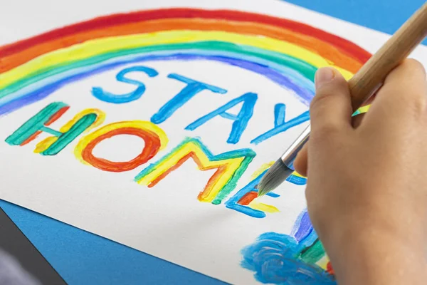 Pintura infantil durante la cuarentena en casa. Arco iris con palabras Quédate en casa. Campaña de medios sociales para la prevención del coronavirus — Foto de Stock