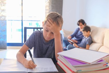 Çocuklar evde öğreniyor. Anne oğluna ödevlerinde yardım ediyor ve dizüstü bilgisayarda çalışıyor. Çevrimiçi öğrenme, çalışma, alışveriş, uzaklık öğrenme, evde kalma kavramı