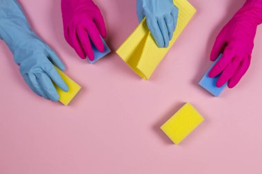 Pembe ve açık mavi kauçuk eldivenli pembe arka planda süngerli kadınlar