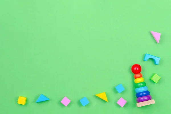 Kinderspielzeug Hintergrundrahmen mit Baby Stapelringe Pyramide und bunte Blöcke auf grünem Hintergrund — Stockfoto