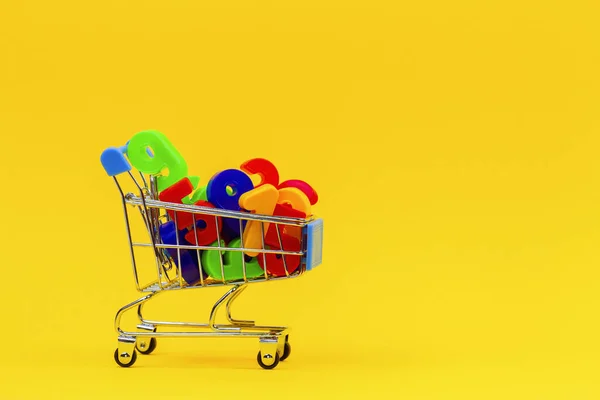 Mini carrinho de compras ou carrinho de supermercado cheio de números coloridos no fundo amarelo — Fotografia de Stock