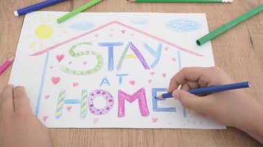 Coronavirus covid-19 salgınını önlemek için sosyal medya kampanyası. Evde karantina sırasında renkli kalemlerle resim yapan bir çocuk. Yazı iletisi ile çiziliyor Evde kalın