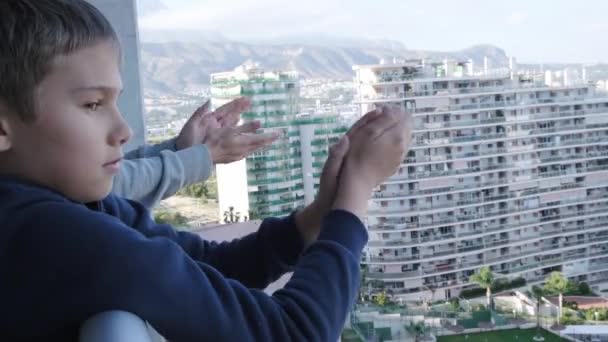Rodzina bije brawo personelowi medycznemu z balkonu. Ludzie w Hiszpanii klaskający na balkonach i oknach wspierających pracowników służby zdrowia podczas pandemii koronawirusowej — Wideo stockowe