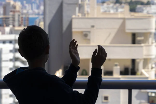 Kind applaudiert medizinischem Personal vom Balkon aus. Menschen in Spanien klatschen während der Coronavirus-Pandemie dankbar auf Balkonen und Fenstern zur Unterstützung von Gesundheitspersonal, Ärzten und Krankenschwestern — Stockfoto