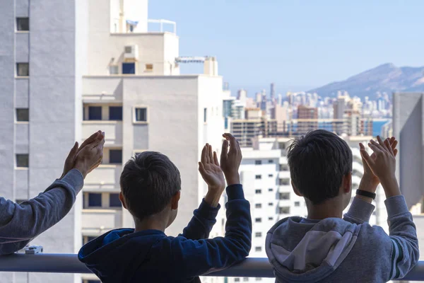Rodzina bije brawo personelowi medycznemu z balkonu. Ludzie w Hiszpanii klaskają wdzięcznością na balkonach i oknach wspierających pracowników służby zdrowia, lekarzy i pielęgniarki podczas pandemii koronawirusowej — Zdjęcie stockowe