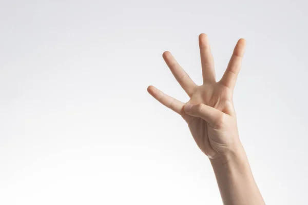 Mano de niño mostrando y apuntando hacia arriba con los dedos número cuatro sobre fondo blanco de la pared — Foto de Stock