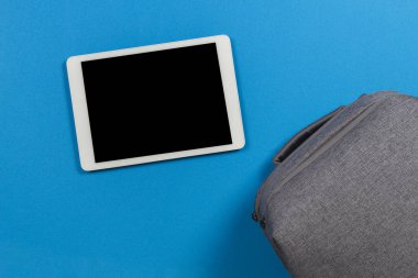 Okul, çevrimiçi öğrenme, uzaktan eğitim. Mavi arka planda dijital tablet bilgisayar ve sırt çantası. Üst görünüm