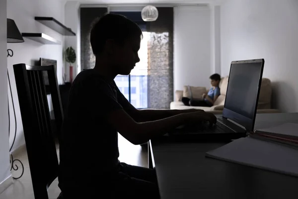 Escola, educação à distância, aprendizagem online em casa. Crianças fazendo lição de casa com computador portátil e cadernos de livros. Silhueta — Fotografia de Stock