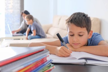 Çevrimiçi öğrenme, evden uzak eğitim. Aile evde. Çocuklar ödevlerini kitaplarla, ders kitaplarıyla ve bilgisayarla yapıyor, anneleri çocuklara yardım ediyor.