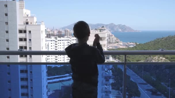 Kind applaudisseert medisch personeel vanaf het balkon. Mensen in Spanje klappen op balkons en ramen ter ondersteuning van gezondheidswerkers tijdens de Coronavirus pandemie — Stockvideo