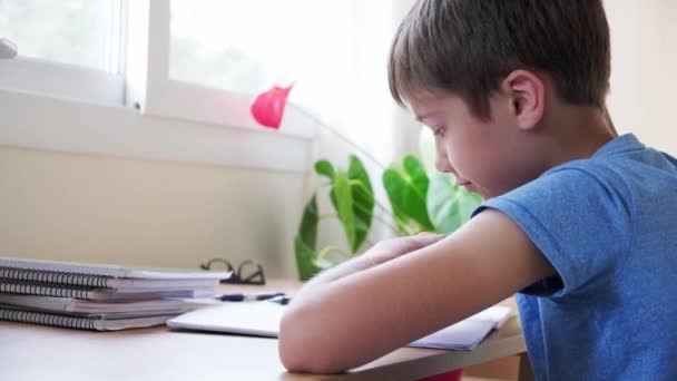 Kid cansado de fazer lição de casa, menino coloca a cabeça nas mãos e não quer aprender — Vídeo de Stock