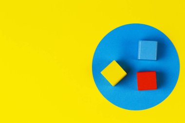 Geometrik sarı arkaplanda ahşap renkli bloklar. Doğal eğitim sıfır, tahta oyuncakları boşa harcıyor. Üst görünüm
