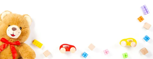 Dětské hračky banner pozadí. Medvídek, dřevěná auta, barevné cihly, bloky na bílém pozadí. Horní pohled — Stock fotografie
