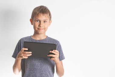 Çocuk dijital tablet bilgisayar tutuyor ve doğrudan kameraya bakıyor. Çevrimiçi öğrenim, eğitim, çocuklar için uzaklık öğrenme