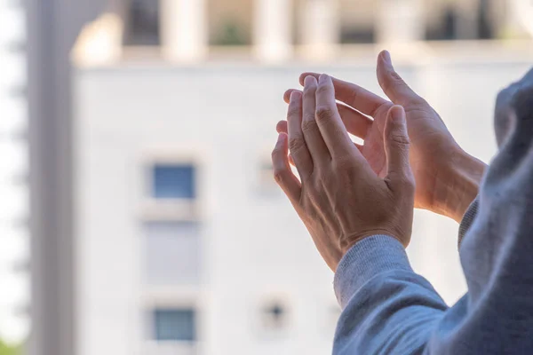 Woman clapping hands, applauding from balcony to support doctors, nurses, hospital workers. Applause to medical staff during Coronavirus pandemic quarantine