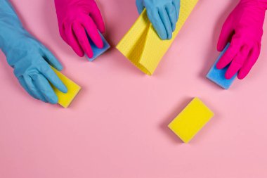 Pembe ve açık mavi kauçuk eldivenli pembe arka planda süngerli kadınlar