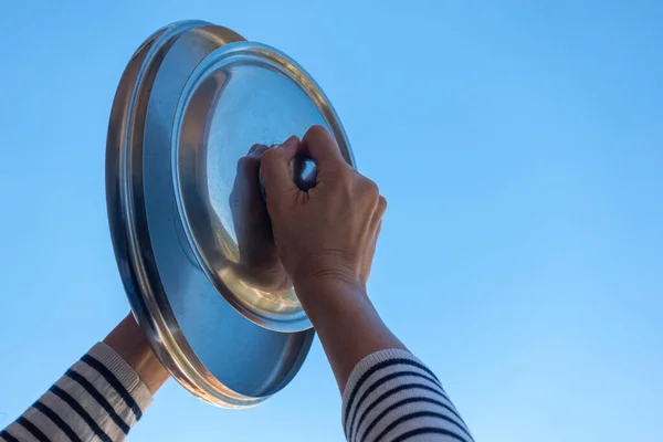 Protest against the government measures. Woman hands banging pot lids against blue sky. Banging pots and pans from the windows and balcony — Stock Photo, Image