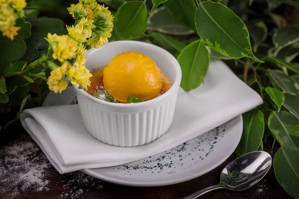 Crema brulee con menta y una cucharada de helado de naranja en un plato blanco —  Fotos de Stock