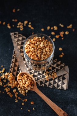 Koyu arkaplanda bardakta klasik granola.