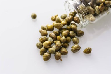 Dağınık turşulu kapari beyaz bir tabakta, yakın plan üst görüntü