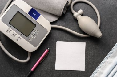 Kan basıncı monitörü ve siyah bir masa üzerindeki notlar için bir kağıt.