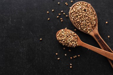 Gri arka planda tahta kaşıklarda yeşil karabuğday