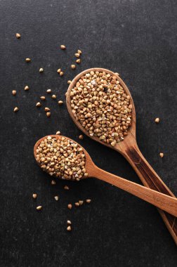 Gri arka planda tahta kaşıklarda yeşil karabuğday