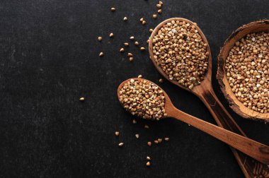 Gri arka planda tahta kaşıklarda yeşil karabuğday