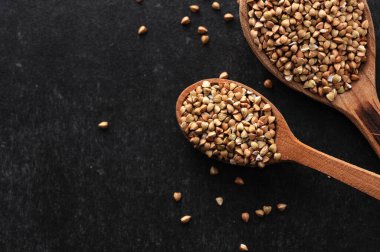 Gri arka planda tahta kaşıklarda yeşil karabuğday