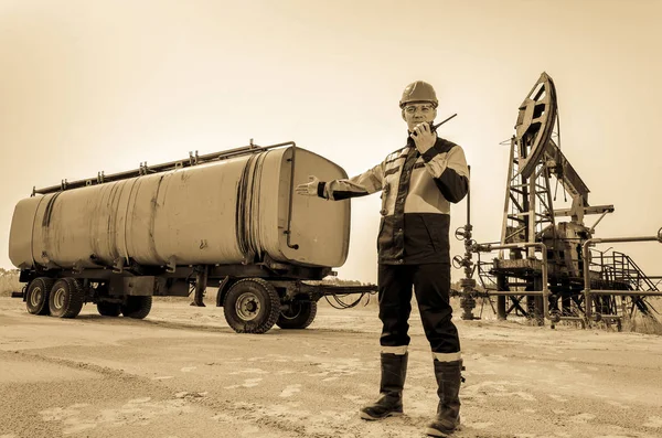 Pracownik w pobliżu pumpjack i cysterny na polu naftowym. — Zdjęcie stockowe