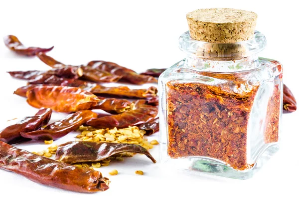 Suché drcené chilli v skleněná láhev a celé chilli lusky a semena — Stock fotografie
