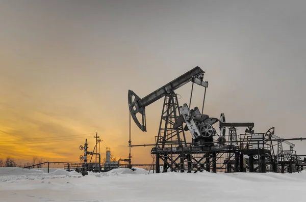Campo petrolífero durante la puesta del sol en invierno — Foto de Stock