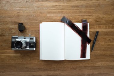 35mm ince tabaka fotoğraf makinesi, defter, kalem, film şeridi ve film rulo lay ahşap masa üzerinde görüntülemek boşaltmak ile üstten