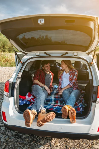 Pareja sentada en coche abierto tronco — Foto de Stock